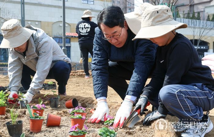 정명근 화성특례시장(가운데)이 21일 동탄여울공원에서 화성특별정원에 아이와 함께 꽃을 심고 있다